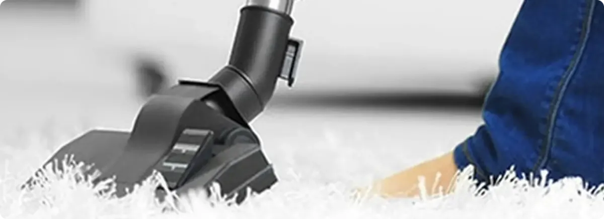 Close-up of a professional vacuuming a white carpet in Tyngsboro.